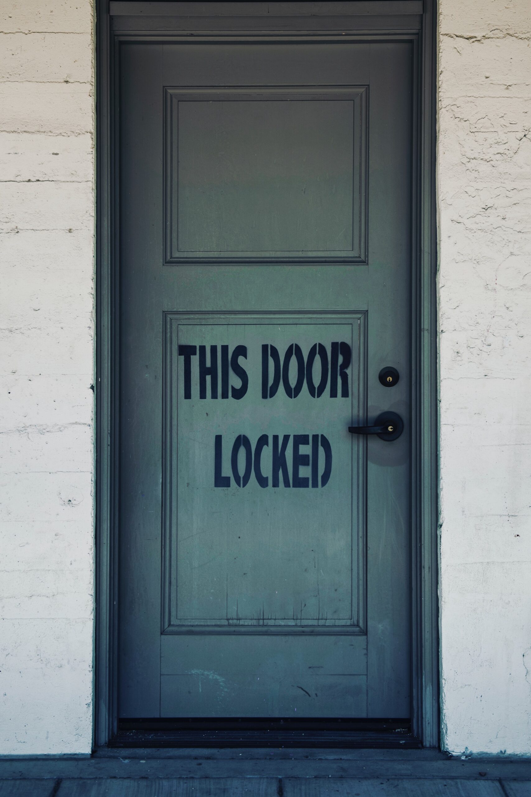 Sage green door with "This door is locked" written on it.